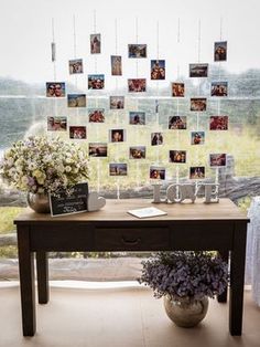 a table with pictures hanging from it and flowers in the vase next to it on top