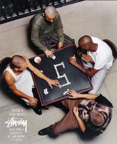 four men sitting at a table playing a game with the number five written on it