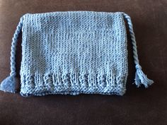 a blue knitted bag sitting on top of a couch