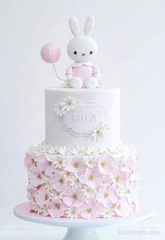 a white cake with pink flowers and a bunny on top that says miffya