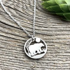 "Bear in Woods Circle Outline Pendant, large and petite The Bear is a symbol of the protector, symbolizing courage, physical strength and leadership. Bears are strong agile and quick. Bear in Woods design encompassed in a circle. Large Charm is 23mm or just shy of 1\", with 18\" Stainless snake snake chain with 2\" extender 18\"-20\". Petite Charm is 17.5 mm approximately 3/4 inch, with 18\" Stainless Link chain with 2\" extender 18\"-20\". Message us for other chain/cord options available inclu Laser Engraved Symbolic Round Jewelry, Minimalist Round Laser Engraved Jewelry, Etched Stainless Steel Jewelry, Etched Round Stainless Steel Jewelry, Etched Stainless Steel Round Jewelry, Bear In Woods, Woods Design, Circle Outline, Locket Bracelet