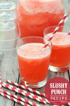 two glasses filled with watermelon juice on top of a wooden table next to red and white striped straws