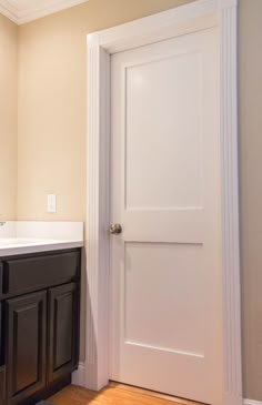 a bathroom with a sink, mirror and door to another room that has wood floors