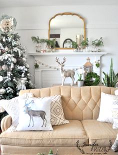 a living room decorated for christmas with a tree in the corner and deer pillows on the couch