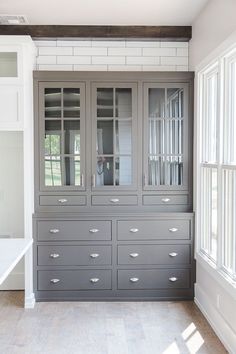 a gray china cabinet with glass doors in a room next to a white counter top