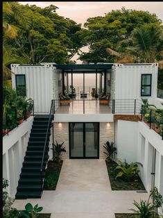 a house made out of shipping containers with stairs leading up to the second floor and patio area