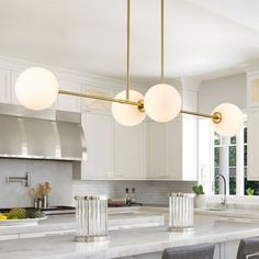 a kitchen with marble counter tops and white cabinets, along with four lights hanging from the ceiling