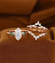 three different types of wedding rings with diamonds and emeralds on the band, set on a brown velvet surface