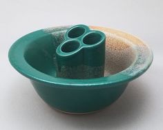 there is a green bowl that has two small cups in it and sand inside the bowl