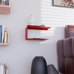 a red shelf on the wall next to a black chair