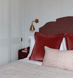 a bed with red and white pillows on top of it next to a night stand