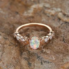 an opal and diamond ring sits on a rock