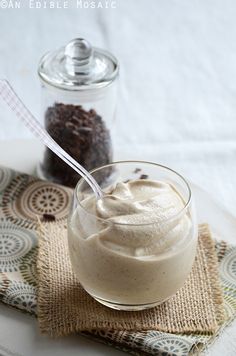 a glass bowl filled with whipped cream on top of a table next to a spoon