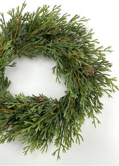 a green wreath with pine cones and needles is shown on a white background, ready to be used as an ornament