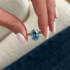 a woman's hand with white and blue manicured nails holding an aqua ring