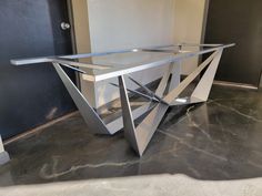 a glass and metal table sitting on top of a cement floor next to a door