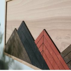 a close up of some wood on a wall with plants in the foreground and an image of mountains behind it