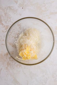 a glass bowl filled with cheese on top of a table