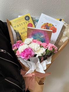 a bouquet of flowers sitting on top of a brown paper bag next to some books