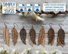 six leather feather earrings hanging from hooks on a wooden background with white flowers in the foreground