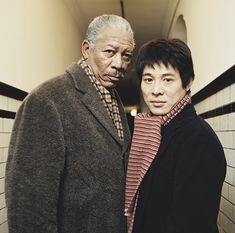 two people standing next to each other in a room with white tiles on the walls