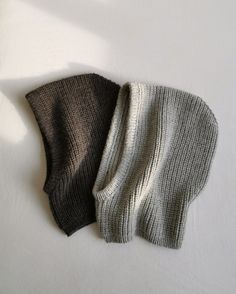 two knitted hats hanging on the wall next to each other, one black and one white