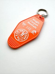 an orange plastic keychain with the words magic carpet rentals printed on it