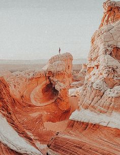 a person standing on top of a rock formation in the middle of an arid area