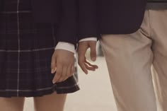 two people standing next to each other wearing skirts and holding hands with one person's hand