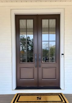 the front door to a house with two double doors and a rug on the floor