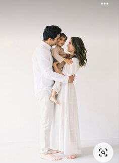 a man and woman holding a baby in their arms while standing next to each other