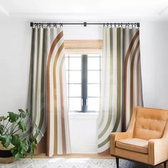 a living room with a chair, window and striped drapes on the windowsill