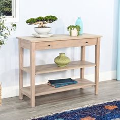 a wooden table sitting on top of a blue rug next to a vase and potted plant