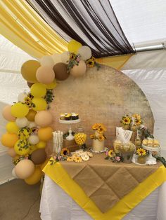 a table topped with cake and desserts under a yellow drape covered tented ceiling