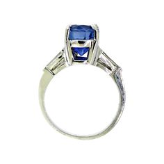 The sapphire in this vintage-style platinum mounting is the most incredible blue. The mixed cut oval is a strongly saturated, violetish blue with a medium dark tone, and moderately included clarity. It's easy to get lost in the deep blue sparkle set off by two tapered baguette diamonds on each side. The platinum mounting is a very sturdy, yet still elegant rendition of the 1940s style. It will stack beautifully with a curved baguette band, or be just as lovely on its own. It's also a nice choice Classic Sapphire Baguette Cut Ring, Classic Oval Sapphire Ring With Polished Finish, Platinum Sapphire Ring With Baguette Cut, Classic Blue Sapphire Ring In Platinum, Sapphire Baguette Cut Platinum Ring, Baguette Cut Sapphire Platinum Ring, Classic Sapphire Ring With Baguette Cut, Classic Cushion Cut Sapphire Ring With Polished Finish, Blue Sapphire Ring With Emerald Cut And Polished Finish