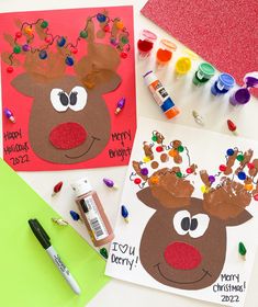 two christmas cards with reindeer faces on them next to some crayons and markers