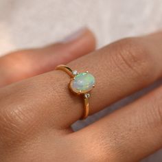 a woman's hand with an opal and diamond ring on top of her finger