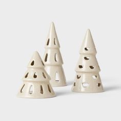 three white ceramic christmas trees on a gray background with holes in the middle and holes at the top