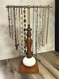 an antique brass plated jewelry stand with beads and shells on the top, in front of a white wall