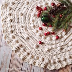 a crocheted placemat with pine cones and berries on it next to a green christmas ornament