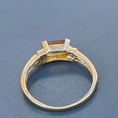 Vintage ~ 10kt solid yellow gold ring with openback ,bezel set faceted Citrine stone ring and three tiny diamonds on each sides ~ Marked 10kt with initials AJ Materials :- 14kt solid gold ( not plated ) genuine Citrine stone (electronically tested ) ..measures 1 1 /8 inches x 3/4 inches wide x approx 1/2 inches in depth Measurements :- ring can fit size 6 1/2 - 7 . Weighs 1 grams on my weighing scale . Condition :- Overall ring is in good vintage condition ~ No cracks /chips to stone . Please No Emerald-cut Yellow Gold Topaz Ring With Bezel Setting, Emerald Cut Yellow Gold Topaz Ring With Bezel Setting, Yellow Gold Three Stone Princess Cut Rings, 14k Gold Three-stone Baguette Cut Ring, 14k Gold Rings With Three Stone Baguette Cut, 14k Gold Three Stone Baguette Cut Ring, 14k Gold Three-stone Emerald Cut Diamond Ring, 14k Gold Three Stone Emerald Cut Diamond Ring, 14k Yellow Gold Moonstone Ring With Center Stone