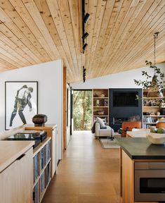 an open kitchen and living room area with wood ceilinging, white walls and cabinets