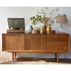 a wooden cabinet with plants and vases on top, next to an old record player