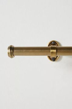 a close up of a metal curtain rod on a white wall