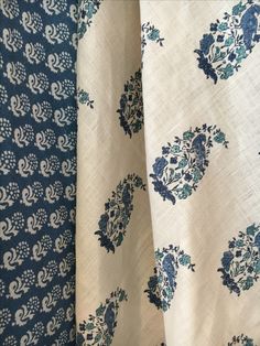 two blue and white curtains with floral designs on them, one in the foreground