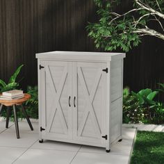 a white cabinet sitting on top of a patio next to a wooden table and chair