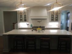 a large kitchen island with three stools in the center and lights on above it