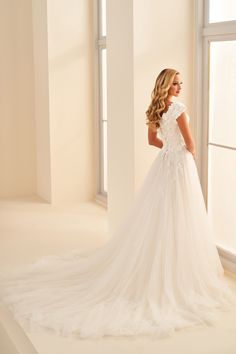 a woman in a wedding dress looking out the window