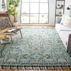 a living room with a couch, chair and rug on the floor in front of a large window