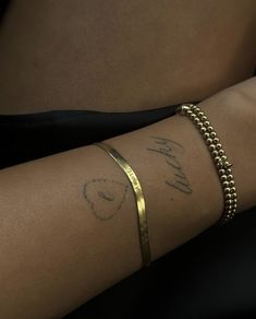 a woman's arm with a gold bracelet and name written on it, in cursive writing